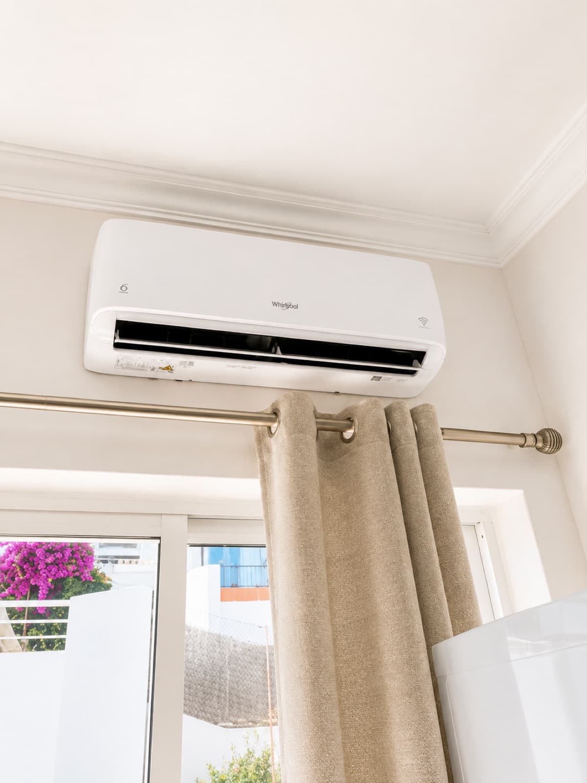 Ar condicionado Whirlpool instalado num quarto, com vista para buganvílias
